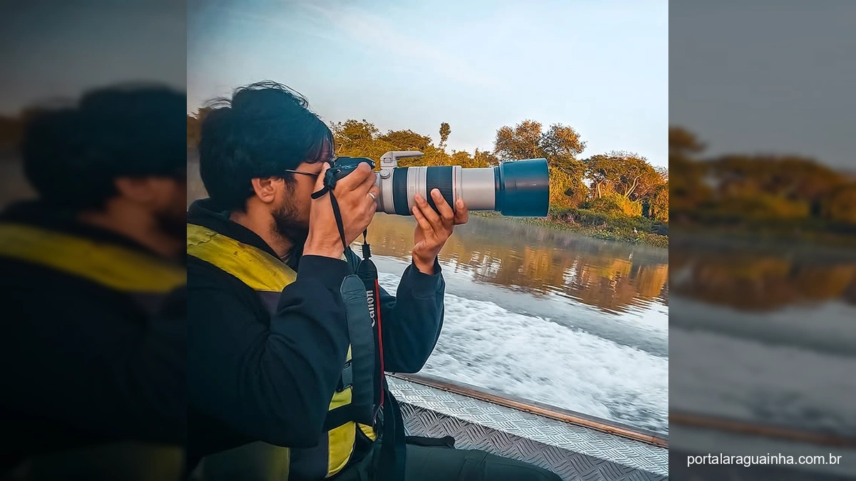 Fotógrafo com câmera grande em barco registrando vida selvagem no Pantanal.