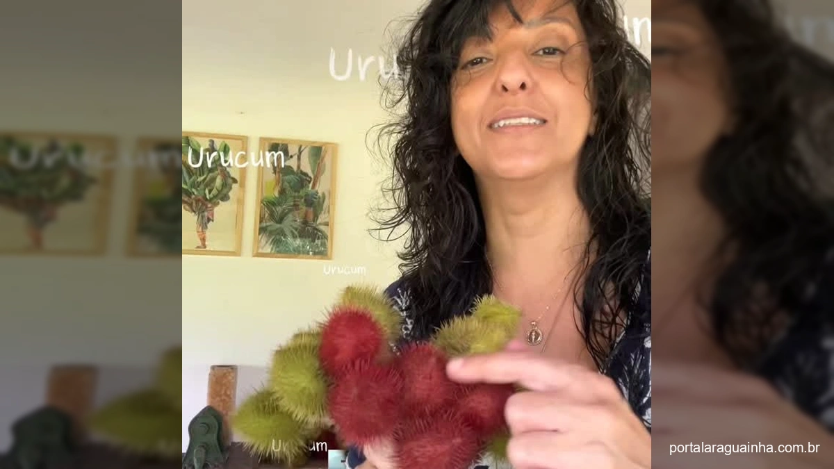 Mulher segurando frutos de urucum vermelho e verde claro (urucum branco), com um fundo de natureza e uma casa.